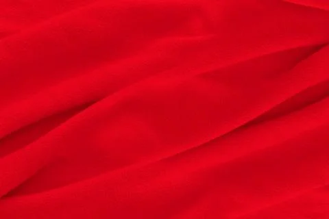 Red fabric texture background. Abstract cloth backdrop with soft waves. Stock Photos