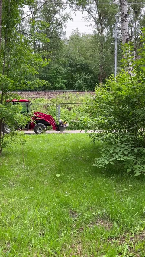 Red farm tractor with green trailer carries park employees and gardeners Stock Footage 270240853