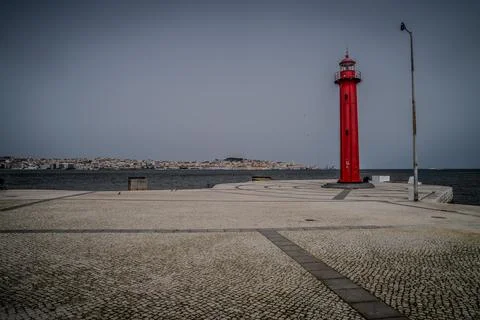 The red Farrobo Lighthouse stands on a circular cobblestone platform extendin Stock Photos