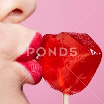 Red female lips shape lollipop. Close-up of woman lips kissing candy. Sweet t Stock Photos