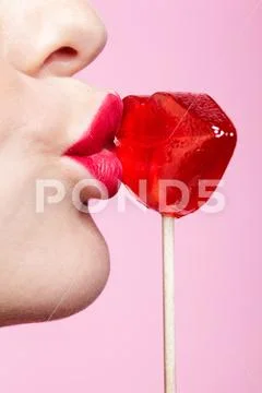 Red female lips shape lollipop. Close-up of woman lips kissing candy. Sweet t Stock Photos