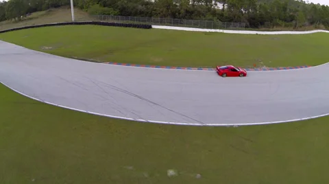 Red Ferrari speeding along on a race track, aerial view Stock Footage
