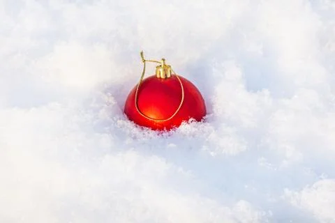 The red festive ball is buried in white snow. New Year and Christmas concept Stock Photos