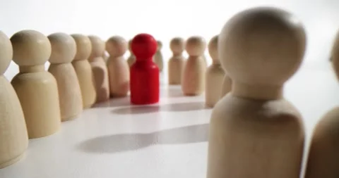 Red figurine stands between long rows of light figures Stock Footage 247406105