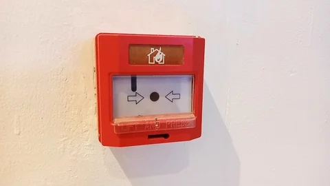 RED FIRE ALARM BUTTON SWITCH WITH ACTIVE BLINKING LIGHT PLACED ON A WHITE  WALL Stock Footage 116088852