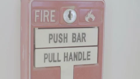 A red fire emergency handle and device is placed on a white wall. It has a Vidéo 138088857