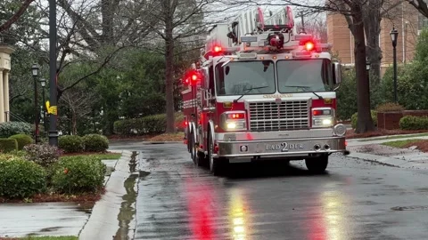 Red Fire Engine with flashing red lights reflecting on a wet road Stock Footage 232053406