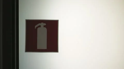 A red fire extinguisher sign hangs on a white wall Stock Footage 272430910