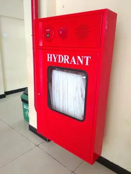 Red fire hose and fire extinguisher cabinets on white hospital wall Stock Photos