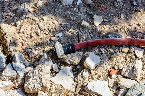 Red fire hose with fitting on the ground Stock Photos