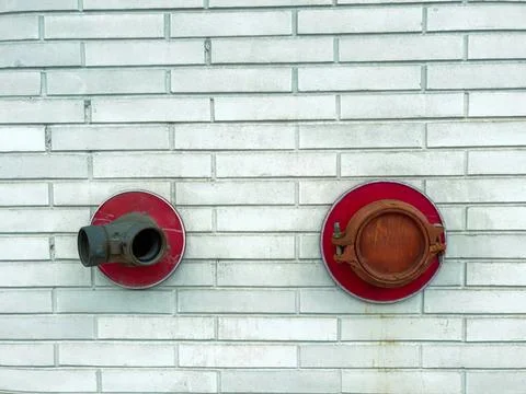 Red fire hydrant and hose reel on brick wall Stock Photos