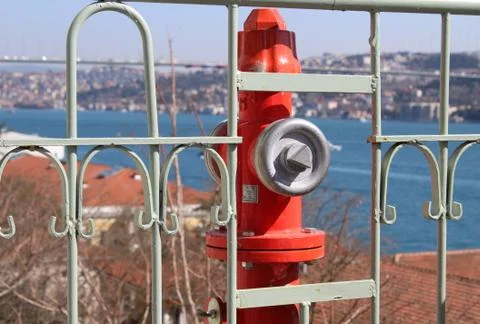 Red Fire Hydrant between the iron railings, backround sea Stock Photos