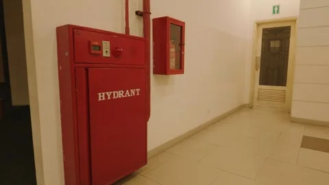 Red fire hydrant cabinet mounted on a white wall in an office corridor. 库存影片 343415044