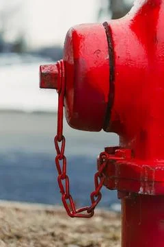Red fire hydrant with chain on city street curb Stock Photos