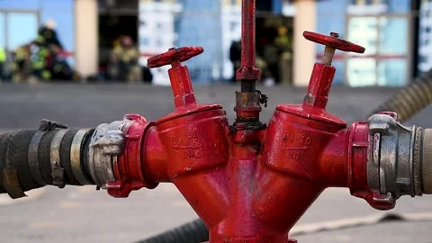 Red fire hydrant with connected hoses against the background of working fir.. Stock Footage 329871207