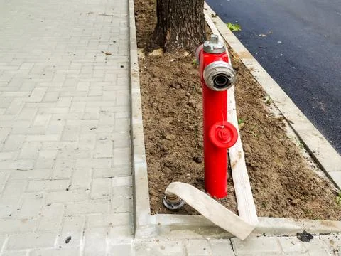 Red fire hydrant with an opened seal and a long white fire hose without water Stock Photos