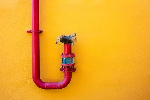 Red fire hydrant pipe on yellow wall background minimal urban design Stock Photos
