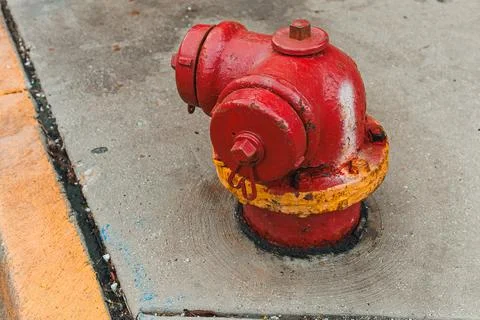 A red fire hydrant is positioned on a concrete sidewalk near a street. The hy Fotos Stock