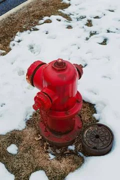 Red fire hydrant on a snowy sidewalk with snow patches Stock Photos