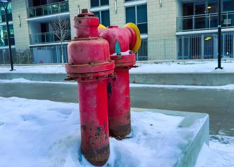 Red fire hydrant on snowy sidewalk in front of building Stock Photos