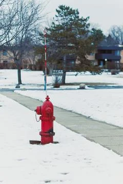 Red fire hydrant stands on a snow-covered sidewalk near a park in winter wi.. Stock Photos