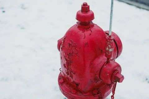 A red fire hydrant stands on a snowy street during winter. The surface shows  Stock Photos