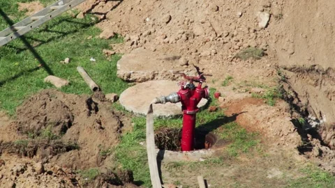 Red fire hydrant sticking out of sewer hatch with water. Concept of fire engine Stock Footage 317090369