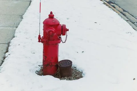 A red fire hydrant is visible in a snowy street. Snow covers the ground, and  Stock Photos