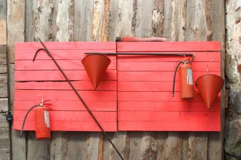 Red fire stand with buckets, hooks, fire extinguishers, axe Stock Photos