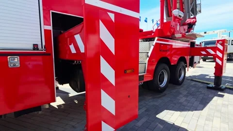 Red fire truck side view detail showing outrigger extension process on paved Stock Footage 341657955