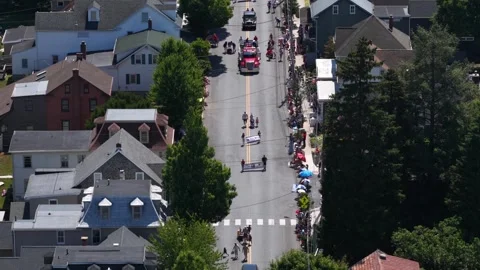 Red fire trucks lead parade procession down tree-lined street in Lititz Video stock 340968607