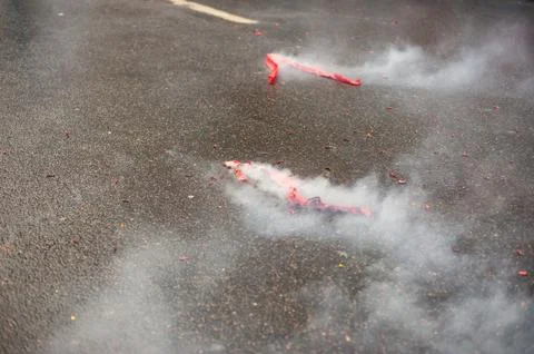 Red firecrackers exploding with smoke on the asphalt 스톡 사진