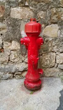 Red fireplug against a stone wall Stock Photos
