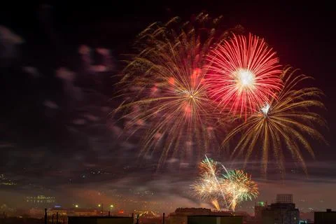 Red firework explosions in the midnight sky. City celebrating holiday. Stock Photos