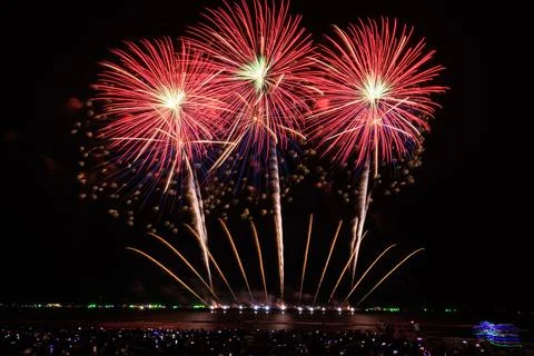 Red Fireworks Exploding Above Coastal Crowd At Night Wide Shot Stock Photos