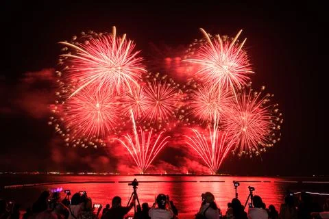 Red Fireworks Exploding Over Beach Crowd Taking Photos At Night Wide Angle .. 스톡 사진