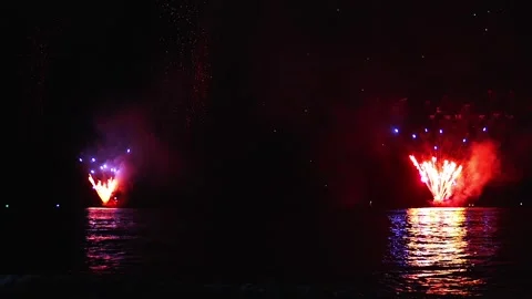 Red fireworks exploding over dark seawater top surface at night Stockbeeldmateriaal 346247835