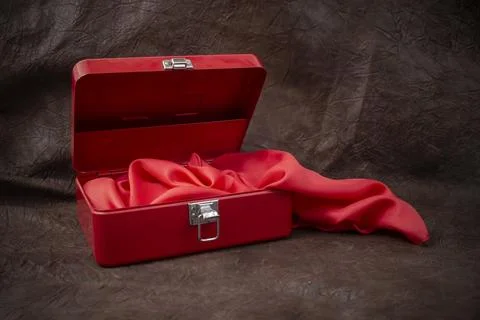 Red first aid kit box, opened with red satin fabric folds on brown genuine .. Stock Photos