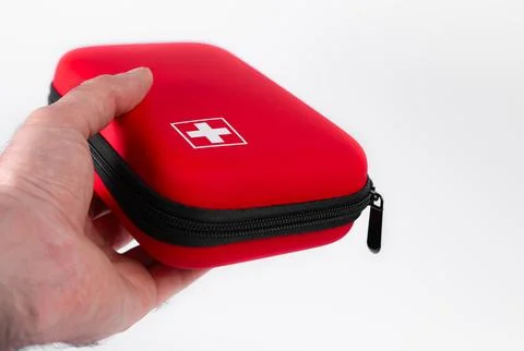 Red first aid kit held in hand ready for emergencies and outdoor activities Stock Photos