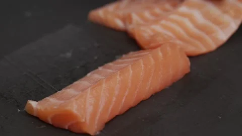 The red fish is cut into slices. Close up shot. Cooking sushi roll. Black textur Video stock 145343413