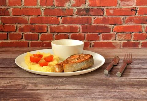 Red fish steak with mashed potatoes and cherry tomatoes in a round plate wi.. Stock Photos