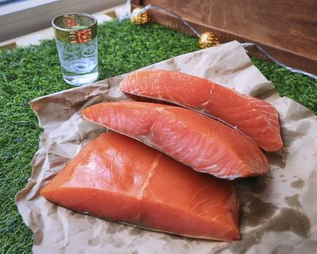 Red fish on the table, a slice of fish, seafood and alcohol, green lawn, salted Stock Photos
