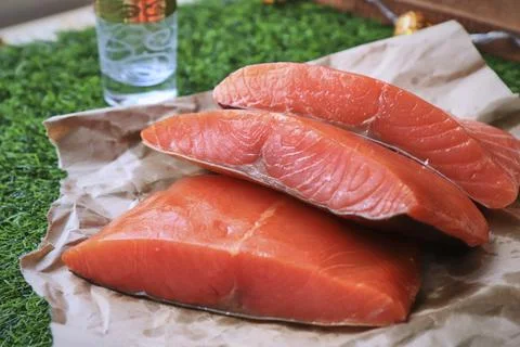 Red fish on the table, a slice of fish, seafood and alcohol, green lawn, salted Stock Photos