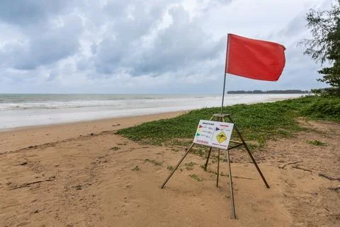 Red flag alert on beach front signaling danger and no swimming is allowed Stock Photos