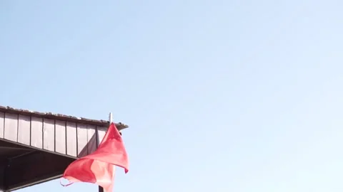 The red flag develops against the background of a blue sky Stock Footage 233147630