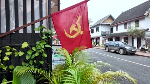 Red flag featuring the hammer and sickle flying from a building facade in Laos Stock Footage 325327109