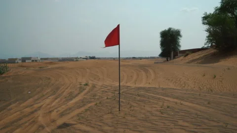 The red flag is fluttering in the wind in the desert. Abandoned al madam village Stock Footage 220871825
