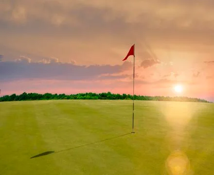 Red flag in a golf course during sunset Stock Photos