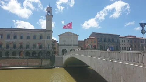 The red flag of Pisa waving in the wind on the bridge "Ponte di Mezzo", Arno Stock Footage 133915245