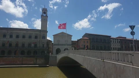 The red flag of Pisa waving in the wind on the bridge "Ponte di Mezzo", Arno Stock Footage 133915264